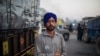 Farmer Harinder Singh, 28, stands for a photograph next to his tractor parked on a highway during a protest against new farm laws, at the Delhi-Haryana state border, India, Dec. 2, 2020. 