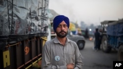 Farmer Harinder Singh, 28, stands for a photograph next to his tractor parked on a highway during a protest against new farm laws, at the Delhi-Haryana state border, India, Dec. 2, 2020. 