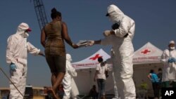FILE - A woman from Nigeria receives a pair of shoes from Italian aid workers, as she leaves the Golfo Azzurro rescue vessel upon their arrival at the port of Pozzallo, south of Sicily, June 17, 2017. 