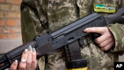 资料照片：一名武装民防妇女手持卡拉什尼科夫突击步枪在乌克兰基辅因宵禁而空荡荡的街道上巡逻。（2022年2月27日）