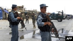Afghan policemen stand guard as two US soldiers (C) arrive at the site of a twin suicide attack near NATO's Kandahar Air Base, June 6, 2012.