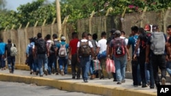 FILE - Central American migrants cross into Mexico from Guatemala, near Ciudad Hidalgo, Mexico, June 4, 2019. The migrants walked over the bridge and waited to register at a Mexican immigration office.