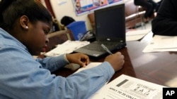 FILE - A student at Roosevelt High School fills out a college enrollment application at her school in Washington, D.C., Nov. 14, 2013.