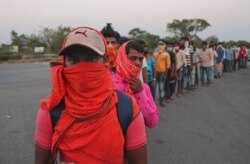 Migrant workers stand to receive food packets from the postal department, on their journey to their home states, during a nationwide lockdown to curb the spread of the coronavirus on the outskirts of Hyderabad, India, May 12, 2020.