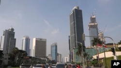 Orang-orang yang memakai masker terlihat menyeberang jalan di kawasan bisnis utama di Jakarta, Senin, 8 Juni 2020. (Foto: AP)