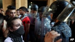 FILE - Riot police stand guard during a demonstration against the political leadership the protesters blame for the economic and financial crisis, in front of the Ministry of Economy, in downtown Beirut, Lebanon, June 6. 2021.