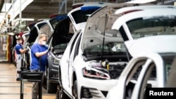 FILE - A worker wears a protective mask at the Volkswagen assembly line after VW re-starts Europe's largest car factory after coronavirus shutdown in Wolfsburg, Germany, April 27, 2020.
