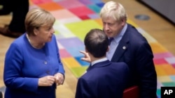 FILE - British Prime Minister Boris Johnson, right, speaks with German Chancellor Angela Merkel, left, and French President Emmanuel Macron during an EU summit in Brussels, Belgium, Oct. 17, 2019.
