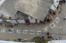 FILE - People keep their bags inside marked areas on a street as they wait to receive free rice distributed at a government store during a nationwide lockdown to prevent the spread of the coronavirus, in Hyderabad, India.