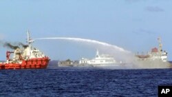 In this photo released by Vietnam Coast Guard, a Chinese ship, left, shoots water cannon at a Vietnamese vessel May 7, 2014. Vietnam tried to stop Beijing from setting up an oil rig in the South China Sea. (AP Photo/Vietnam Coast Guard)