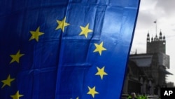 Bendera Uni Eropa dipegang oleh seorang demonstran, dengan latar belakang Menara Victoria, di luar Istana Westminster, di London, Senin, 14 Desember 2020, selama protes saat pembicaraan perdagangan Brexit berlanjut. (Foto: Foto AP/Alberto Pezzali)