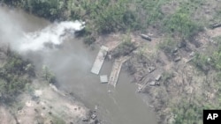 乌克兰武装部队2022年5月12日提供的照片显示乌东北顿涅茨克河上一座被乌军摧毁的俄军浮桥,河两岸是被击毁或损坏的俄罗斯装甲车辆。