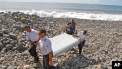 French police officers carry a piece of a plane wing found on Saint-Andre, Reunion Island, last month.