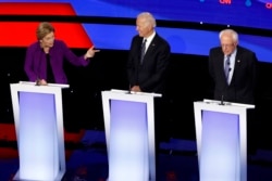 Democratic presidential candidate Sen. Elizabeth Warren, D-Mass., left, speaks to Sen. Bernie Sanders, I-Vt., right as former Vice President Joe Biden watches Tuesday, Jan. 14, 2020, during a Democratic presidential primary debate.
