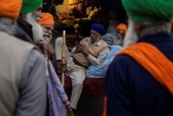 Farmers talk during a protest against the newly passed farm bills at Singhu border near Delhi, India, Dec. 3, 2020.