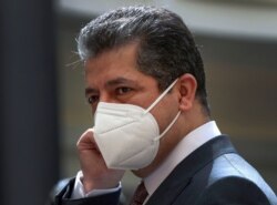 FILE - Prime Minister of the Regional Government of Iraqi Kurdistan Masrour Barzani adjusts his protective mask as he waits for the arrival of the Iraqi prime minister in the capital of the northern Iraqi Kurdish autonomous region, Sept. 10, 2020.