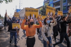 This photo received from an anonymous source via Facebook March 26, 2021, shows protesters carrying signs during a demonstration against the military coup in Yangon, Myanmar.