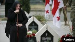 FILE - A woman mourns at the grave of a Georgian soldier killed during Georgia's conflict with Russia over the breakaway region of South Ossetia in 2008 during a ceremony at the memorial cemetery in Tbilisi, Georgia, Aug. 8, 2015. 
