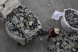 FILE - A worker distributes electronic waste at a government managed recycling center at the township of Guiyu in China's southern Guangdong province, June 10, 2015.