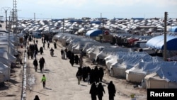 FILE - Women walk through al-Hol displacement camp in Hasaka governorate, Syria, April 1, 2019.