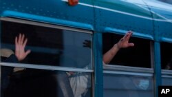 FILE - In this May 4, 2020, file photo, Guatemalans deported from the U.S., wave from a bus after arriving at La Aurora airport in Guatemala City.