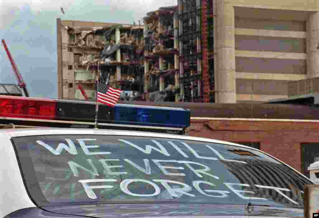 FILE - In this April 24, 1995 file photo, an Oklahoma City police car decorated with the words, "We will never forget," and a small American flag sits near the Alfred P. Murrah Federal Building in Oklahoma City.