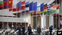 Lao police officials stand next to flags of various nations on display at Wattay International Airport in Vientiane, Laos, Sunday, Nov. 4, 2012.