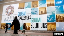 People walk outside the International Monetary Fund headquarters at the start of the annual IMF-World Bank fall meetings in Washington, D.C., Oct. 8, 2013. 