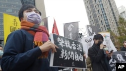FILE - A supporter holds a sign reading 'Support Press Freedom in Hong Kong' to protest outside of the Bank of China in Taipei, Dec. 30, 2021.