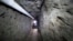 FILE - Federal Police officer stands in the tunnel where drug lord Joaquin "El Chapo" Guzman made his escape from the Altiplano maximum security prison in Almoloya, west of Mexico City, July 16, 2015.