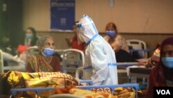 Seorang petugas kesehatan berbicara dengan seorang perempuan di pusat karantina pasien COVID-19 di New Delhi, India, Senin, 19 April 2021. (Foto: Manish Swarup/AP)