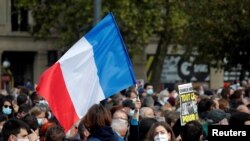 People gather at the Place de la Republique in Paris, to pay tribute to Samuel Paty, the French teacher who was beheaded on the streets of the Paris suburb of Conflans-Sainte-Honorine, Oct. 18, 2020. 