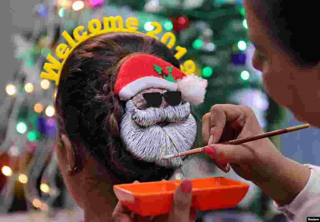 A make-up artist creates a Santa Claus shape in a woman's hair, during New Year's preparations in Ahmedabad, India, Dec. 31, 2018.