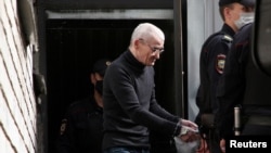 Russian historian Yuri Dmitriev, who was charged with sexually abusing his foster daughter, is escorted by police officers after a court hearing in Petrozavodsk, Russia, July 22, 2020, in this screen grab taken from video.