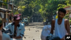 Railway workers, participants of a 'civil disobedience movement' (CDM) against the military takeover of power leave their government provided houses with their belongings as riot policemen watch in Yangon, Myanmar, March 10, 2021. 