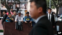 Chinese security officers stand guard as fans carrying jerseys and shoes wait for NBA players to autograph outside the Ritz-Carlton hotel in Shanghai, China, Thursday, Oct. 10, 2019. 