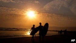 FILE - Surfers are silhouetted during sunset in the Venice Beach section of Los Angeles, California, June 16, 2021. An unusual heat wave is forecast for the coming week for northern California and other parts of the U.S. Pacific Northwest. 
