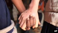 Mina Godfrey, right, holds hands with her friend Charity Kamwendo at her school in this May, 24, 2016 photo taken in Machinga, north east of Blantyre Malawi.