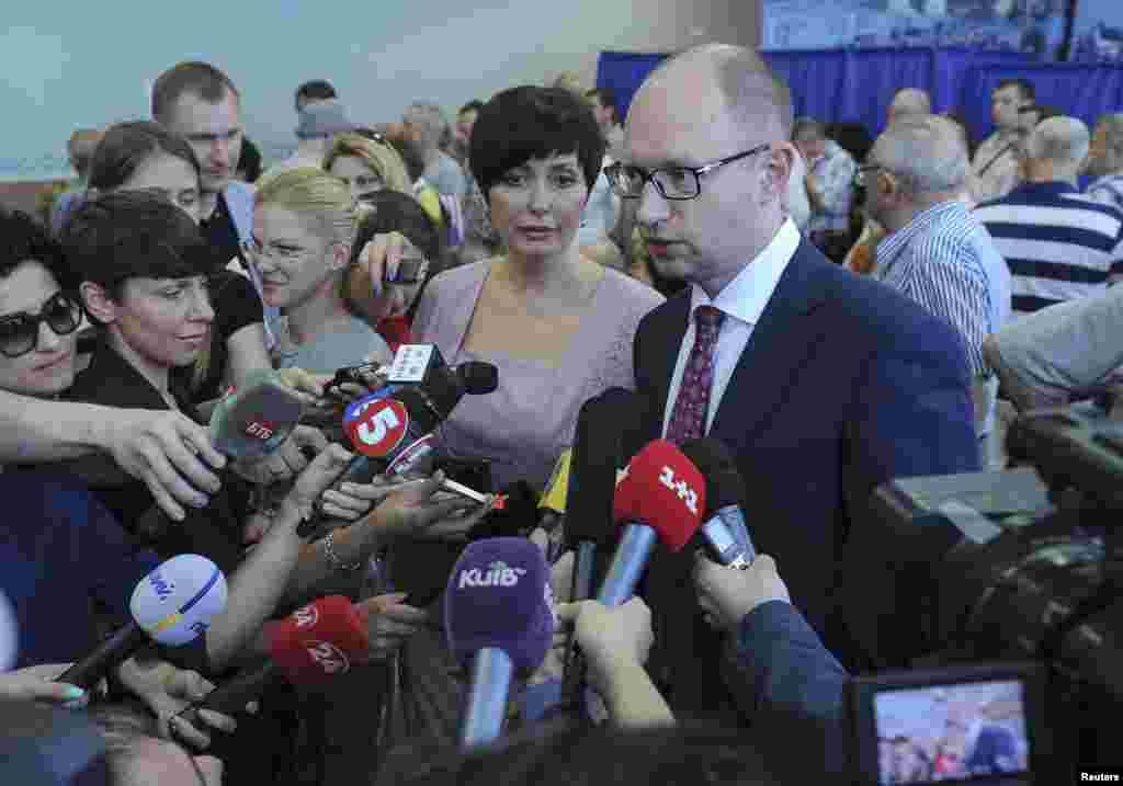 Ukraine's Prime Minister Arseny Yatseniuk (R) accompanied by his wife Teresiya (C) speaks to journalists after voting in a presidential election at polling station in Kyiv.