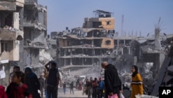 FILE - Warga Palestina berjalan melewati kehancuran setelah serangan udara dan darat Israel di Khan Younis, Jalur Gaza selatan, Senin, 8 April 2024. (AP/Fatima Shbair)