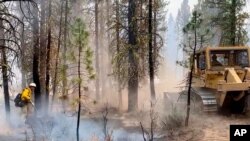 In this photo provided by the Bootleg Fire Incident Command, firefighters battle the Bootleg Fire in southern Oregon, July 17, 2021. 