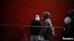 Women wearing face masks and face shields talk on a street, as COVID-19 outbreaks continue in Shanghai, China, Dec. 12, 2022. 