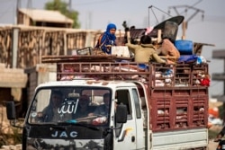 FILE - Displaced Syrians sit in the back of a pick-up truck as Arab and Kurdish civilians flee amid Turkey's military assault on Kurdish-controlled areas in northeastern Syria, Oct. 11, 2019.
