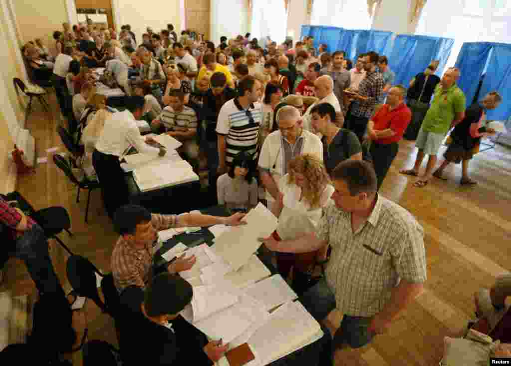 People queue to collect their ballot papers during voting in a presidential election at a polling station in Kyiv, May 25, 2014. Ukrainians voted in a presidential election billed as the most important since they won their independence from Moscow 23 years ago.