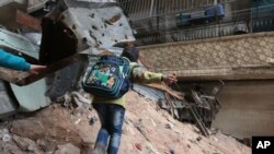 ក្មេង​ម្នាក់​កំពុង​ដើរ​ក្បែរកម្ទេច​អាគារ​និង​ប​ន្លាលួស​នៅ​ក្នុង​ទីក្រុង Aleppo ប្រទេស​ស៊ីរី កាល​ពីថ្ងៃទី១១ ខែ កុម្ភៈ ឆ្នាំ២០១៦។