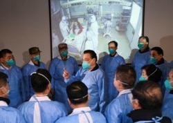 Chinese Premier Li Keqiang, wearing a mask and protective suit, speaks to medical workers as he visits the Jinyintan hospital where the patients of the new coronavirus are being treated, in Wuhan, Hubei province, China, Jan. 27, 2020.