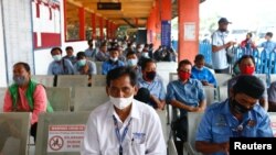 Orang-orang mengenakan masker saat antre untuk divaksinasi COVID-19 dengan vaksin AstraZeneca dalam program vaksinasi massal untuk pekerja transportasi di terminal bus Kampung Rambutan di Jakarta, 11 Juni 2021. (REUTERS/Ajeng Dinar Ulfiana)