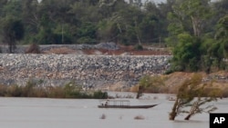 FILE - A fishing boat passes near a construction site of the Don Sahong dam, near the Cambodia-Laos border, June 20, 2016.