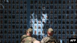 Двоє українських військових перед "Стіною пам’яті полеглим за Україну" у центрі Києва, 20 травня 2024 року. На думку історика Тімоті Снайдера, Україна своїм спротивом "продовжує 1938 рік", дозволяючи уникнути війни між великими державами. (Фото Анатолія СТЕПАНОВА / AFP)