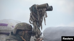 A service member of the Ukrainian armed forces uses binoculars while observing the area at fighting positions on the line of separation near the rebel-controlled city of Donetsk, Ukraine, April 6, 2021.